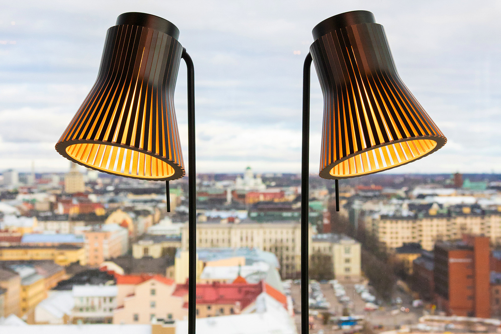 Zwei Petite Tischleuchten vor einem Fenster. Ein Ausblick auf Helsinki im Hindergrund.