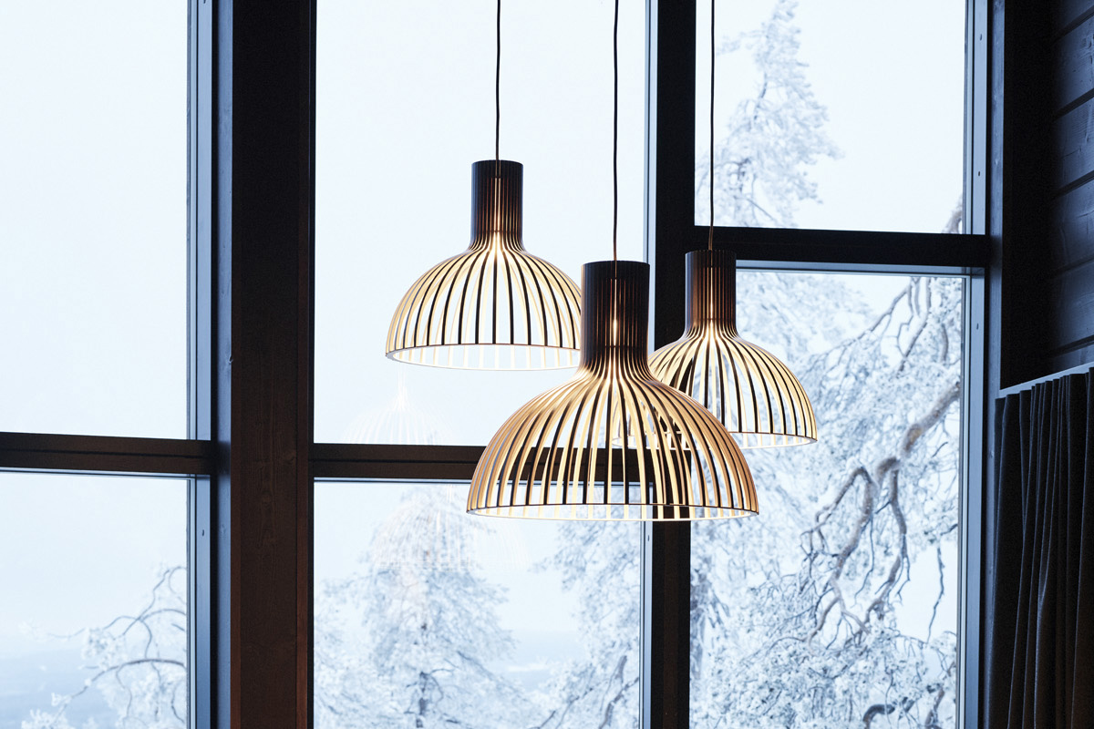 Three Victo pendant lamps hanging in front of large windows with snowy trees in the background.