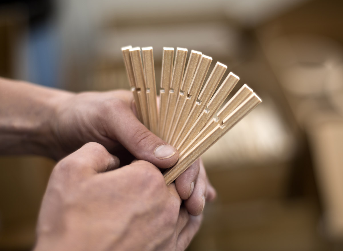 Hands hold wood slats that fan out.