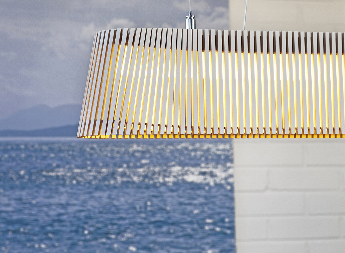 A close-up of the white Owalo pendant lamp. There is an image of the ocean and a white brick wall in the background.