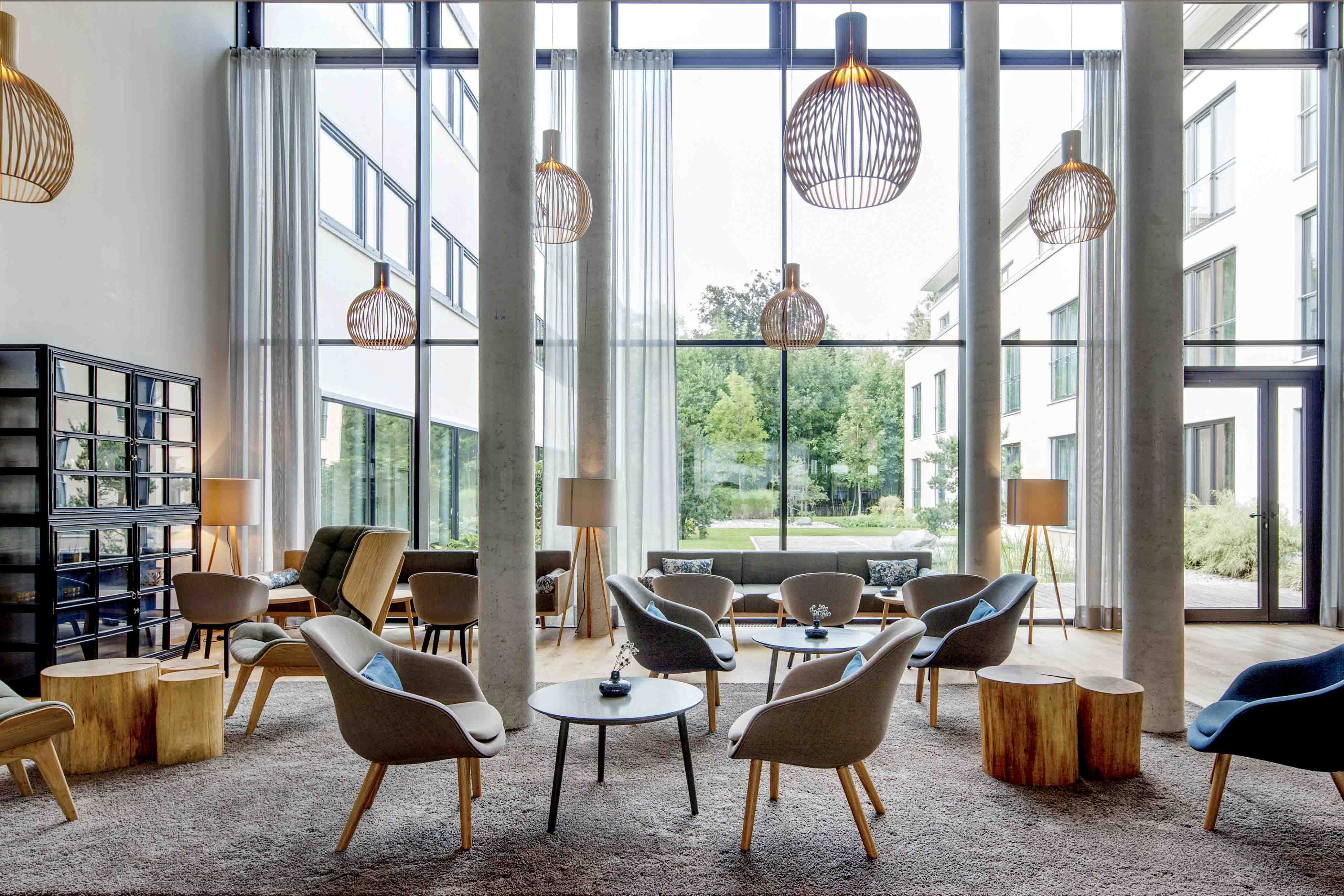 Eine Hotellobby mit Octo Leuchten. Ein Großes Fester mit Blick auf den Garten.