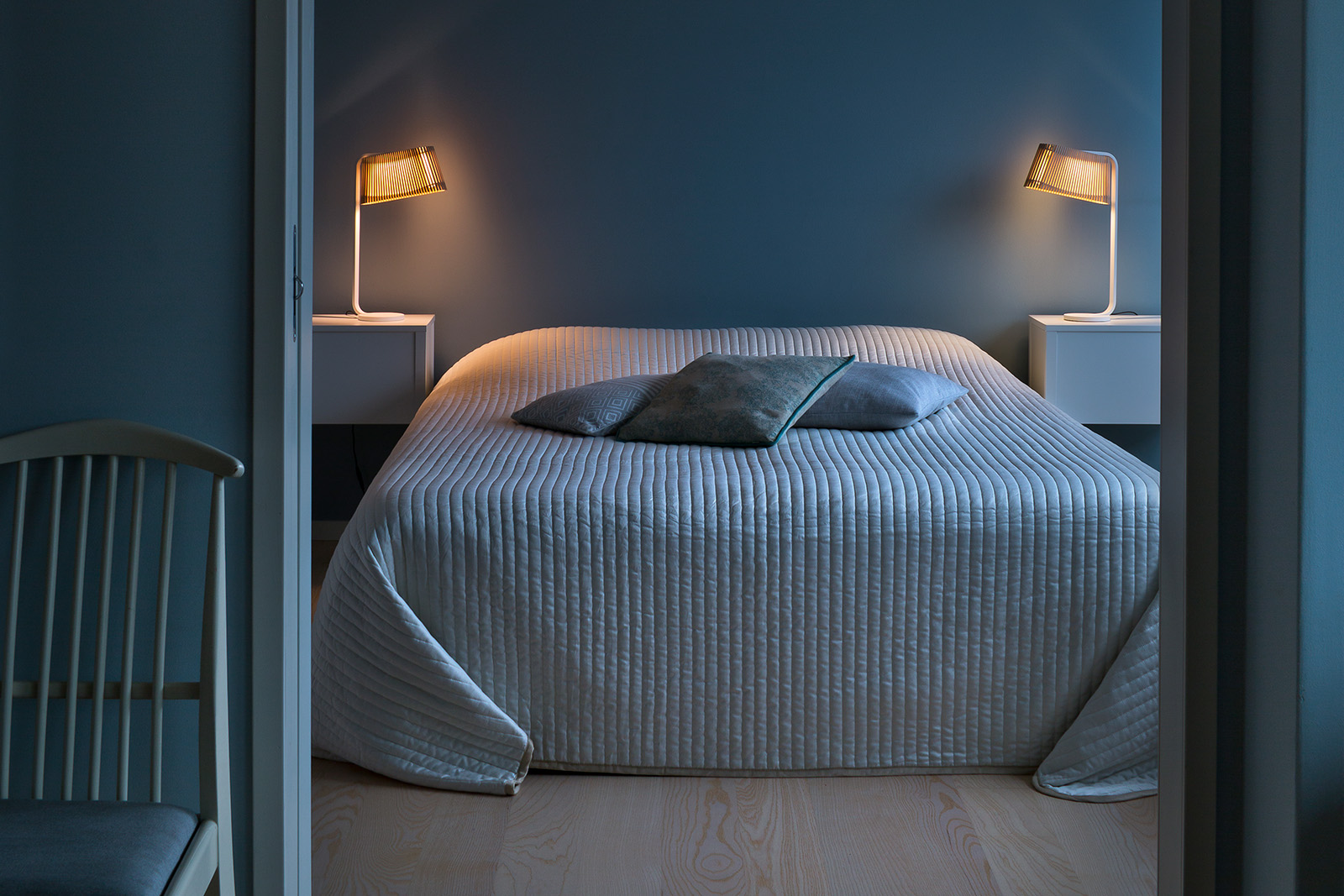Ein Schlafzimmer mit einem Bett, Kissen und Tischleuchten auf den Nachttischen.