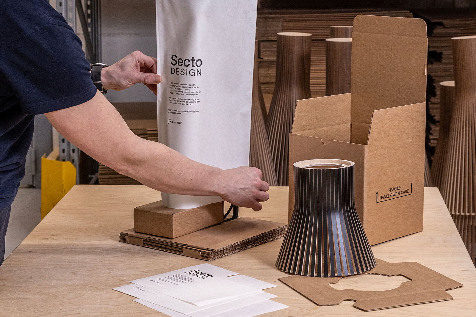 Eine Person verpackt eine Leuchte im Werk von Secto Design.