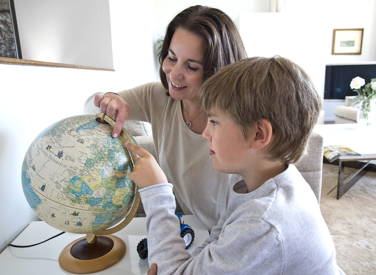 Mother and son looking at a globe, pointing at Finland.