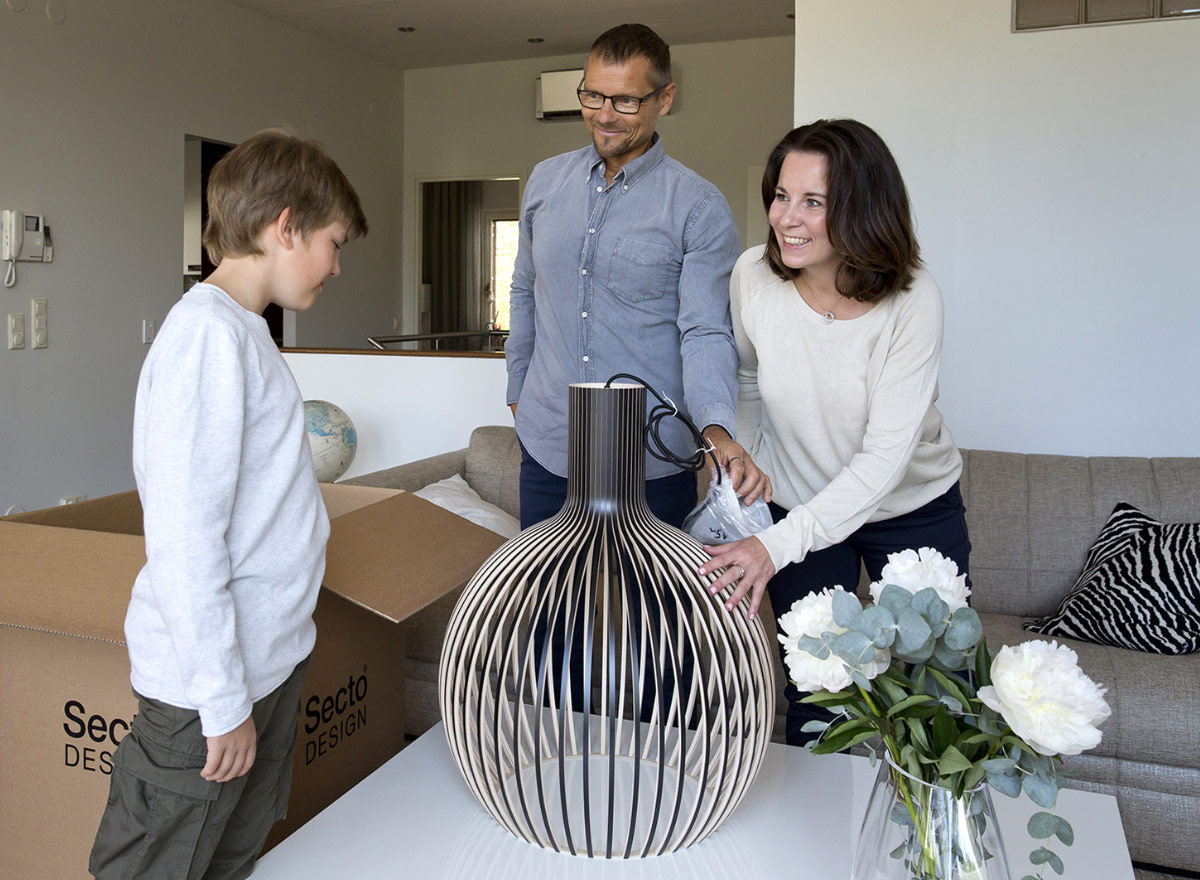 Parents and their son looking at their new classic Octo pendant lamp that is resting on a coffee table.