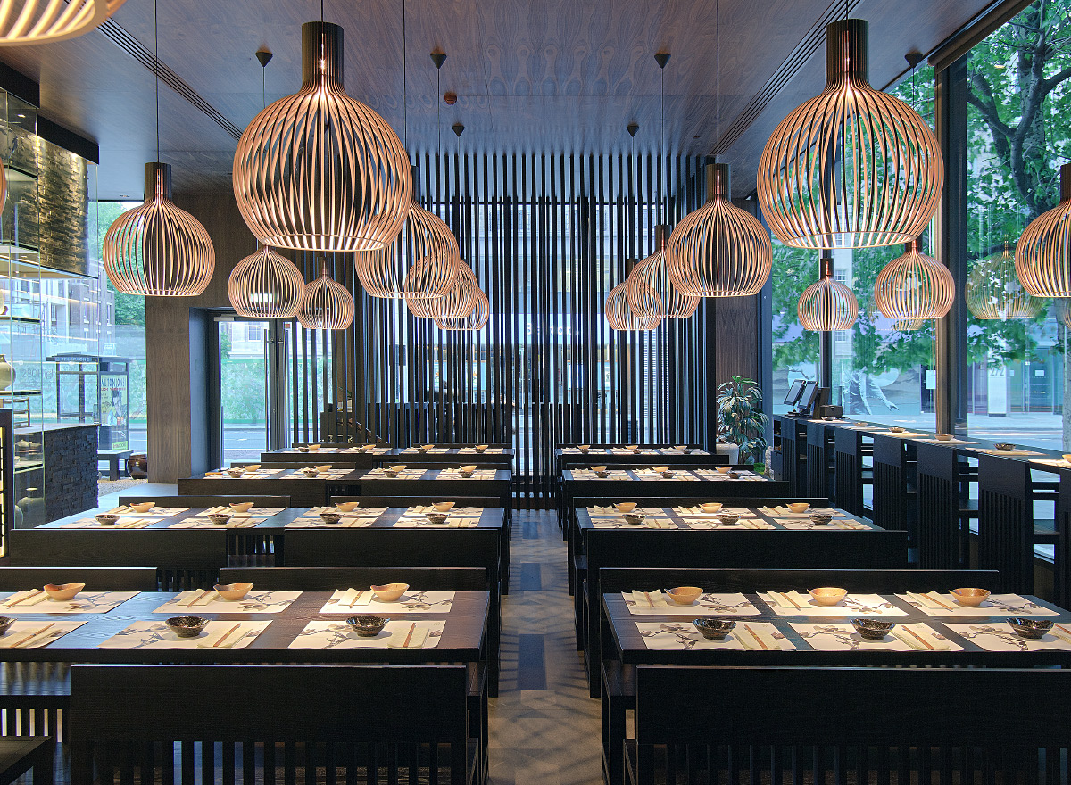 Large, round, wooden Octo pendant lamps above tables in a restaurant. Windows in the background.