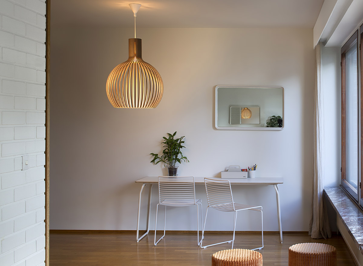 The Octo 4240 pendant lamp, a plant, a mirrow, table and two chairs.