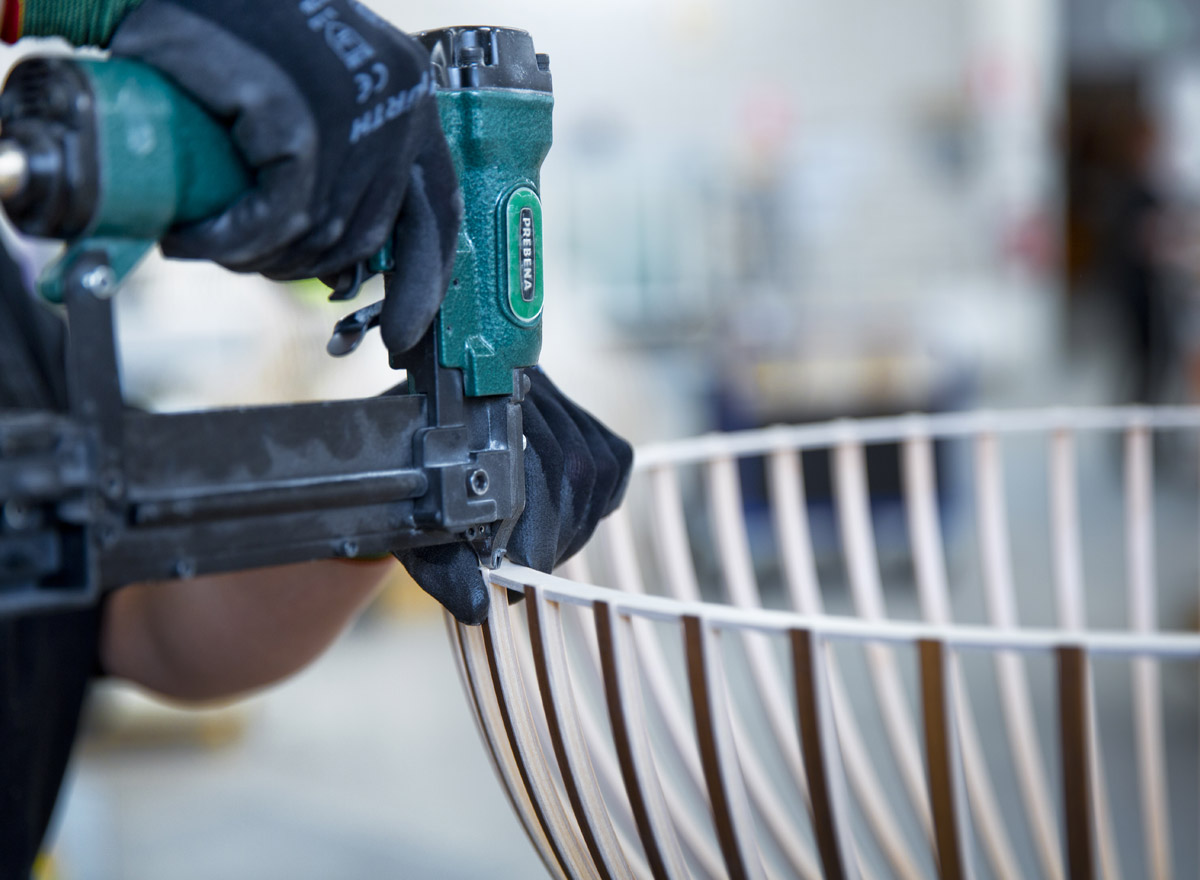 A hand holding a nailing machine. The slats are nailed to the ring.
