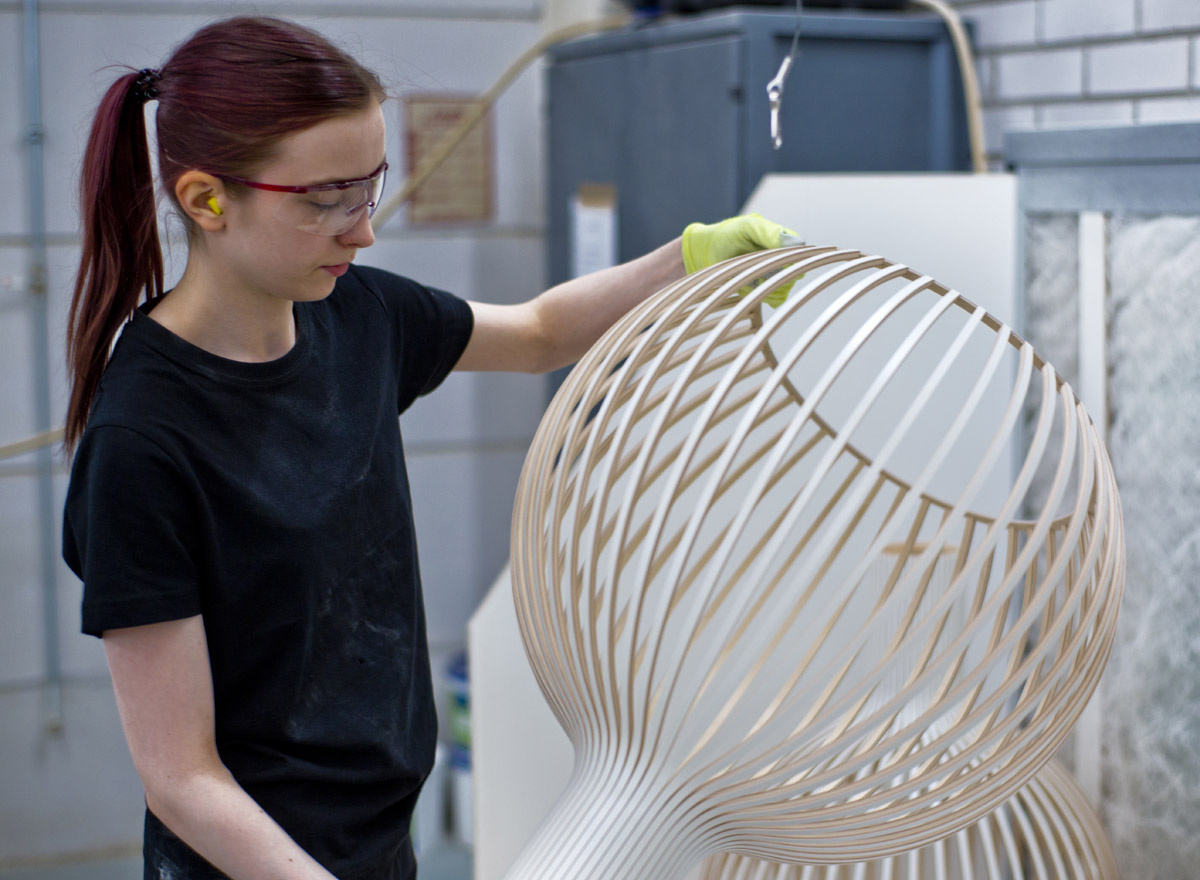 A female factory employee holding and examining an Octo pendant lamp.