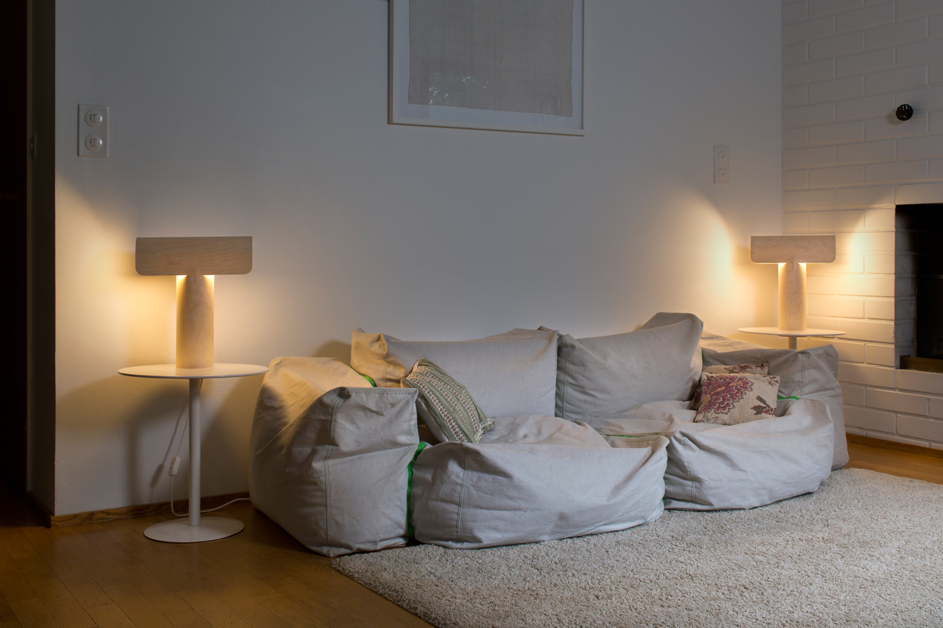 Two Teelo table lamps in birch on top of side tables on either side of a sofa.