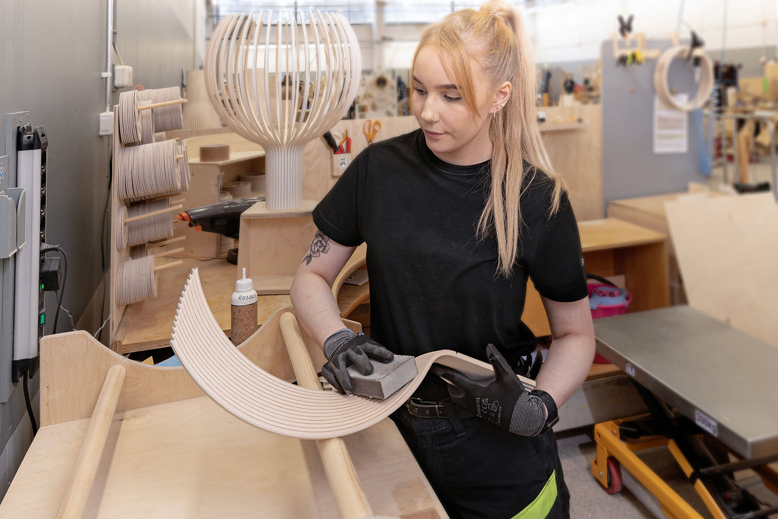 A woman sanding off wooden slats.