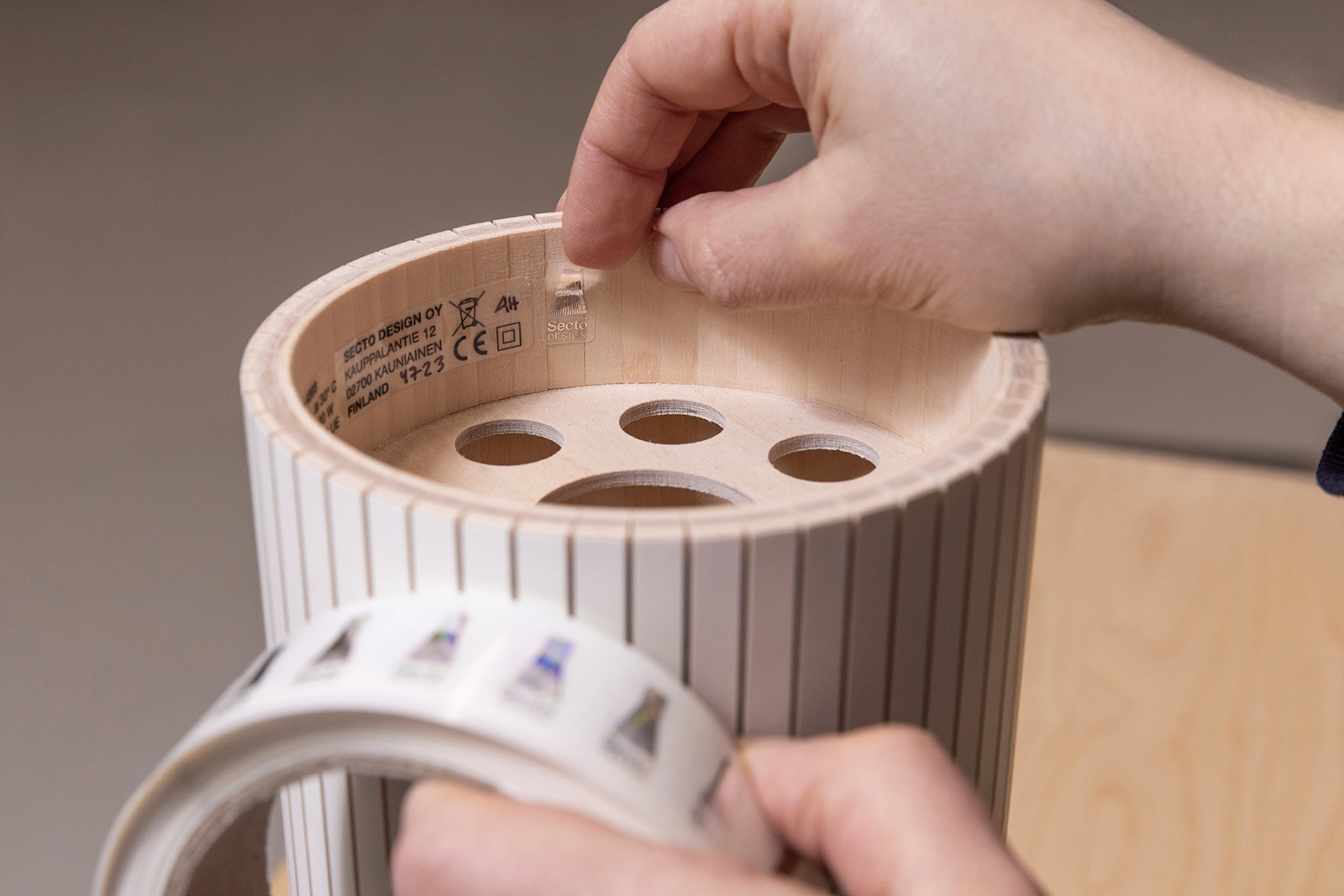 A hand placing a hologram sticker to a lamp from a sticker roll.