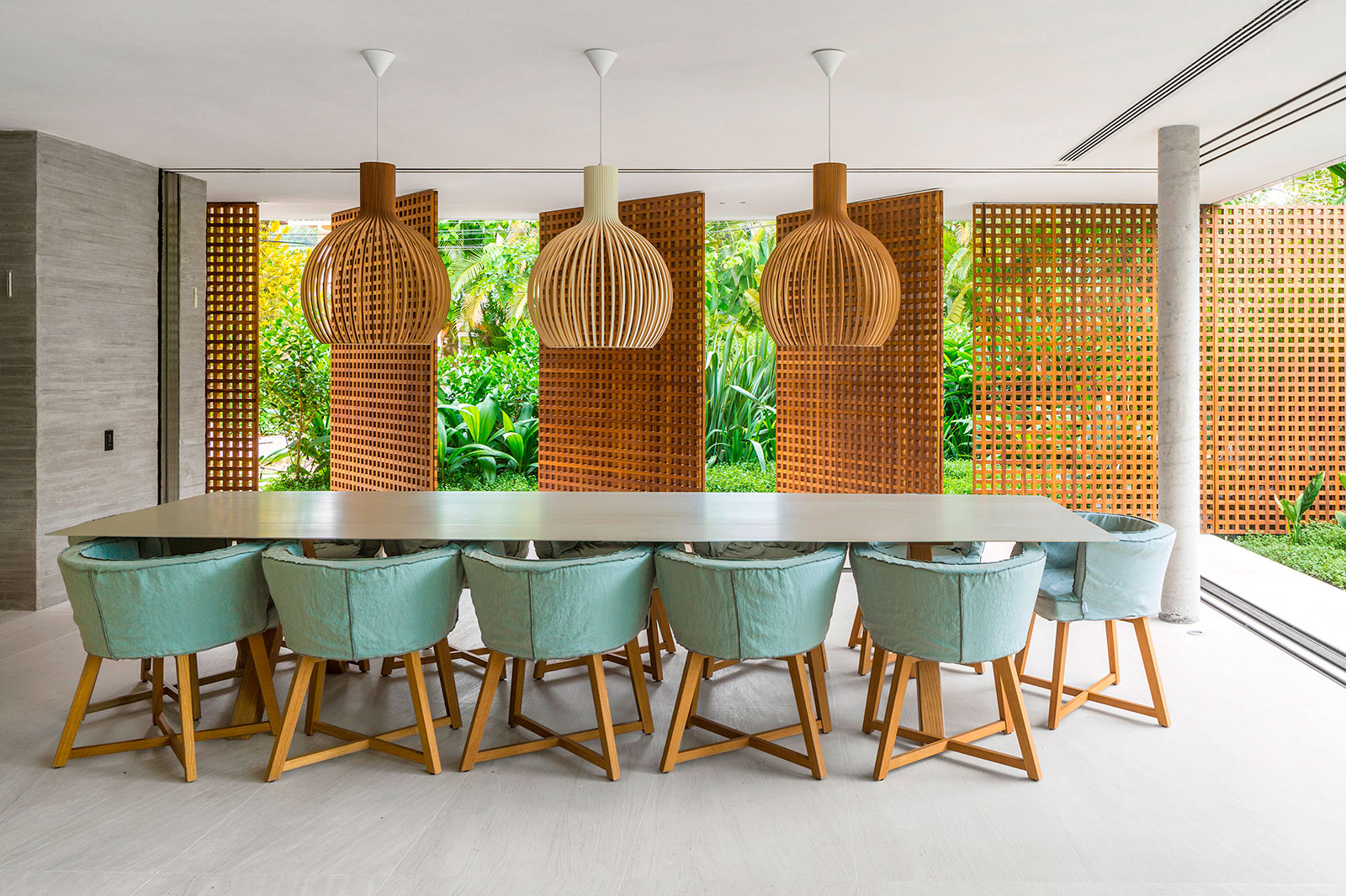 Une longue table à manger avec trois lampes Octo suspendues au-dessus. Deux d'entre elles sont en placage de noyer et l'autre en bouleau.