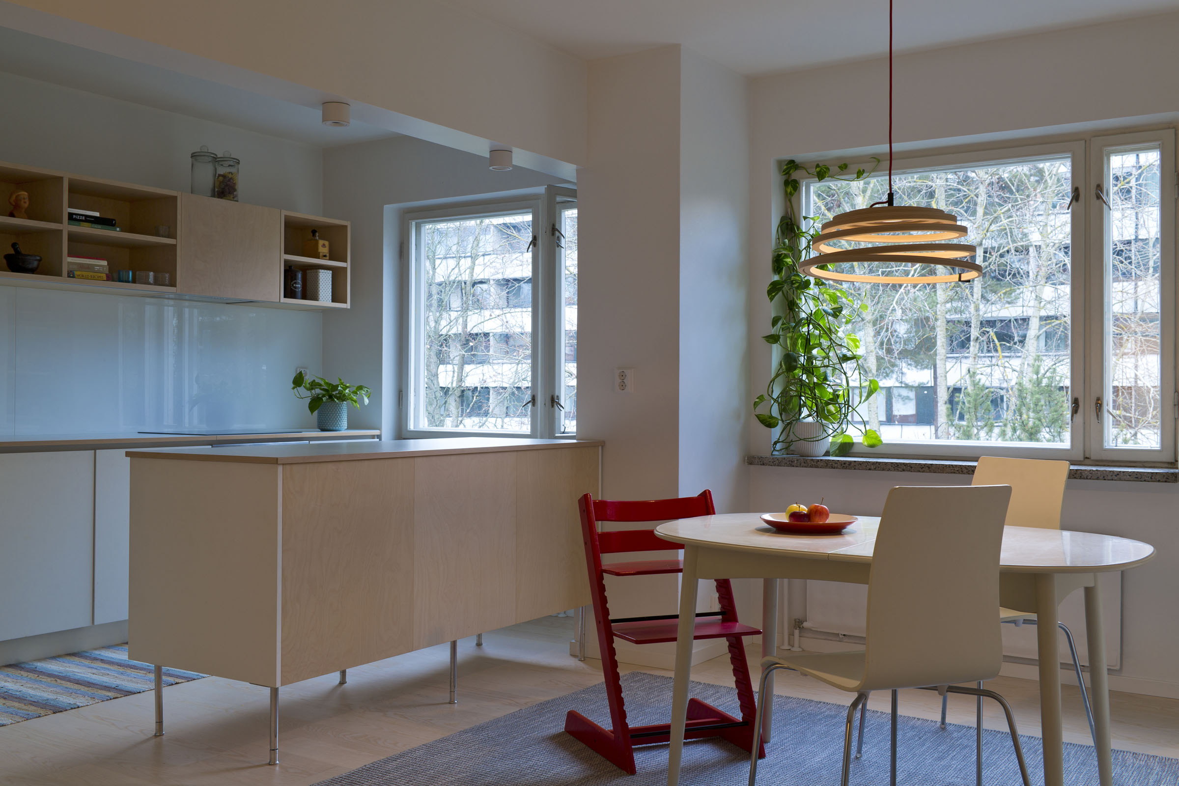 Une salle à manger avec une chaise blanche et une chaise d'enfant rouge près de la table. La lampe Aspiro est suspendue au-dessus de la table.
