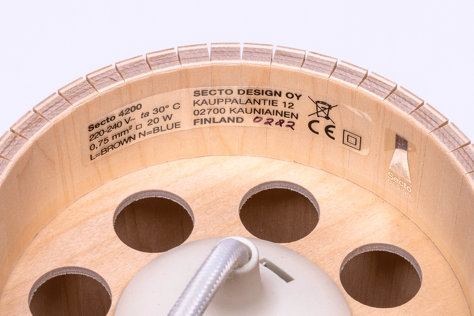 Gros plan d’un label de certification sur une suspension en bois indiquant des marquages d’homologation de sécurité.