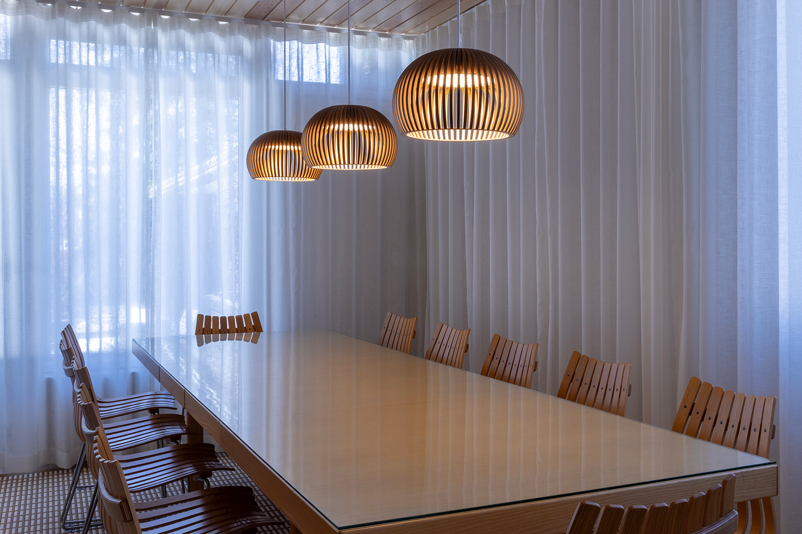 Trois suspensions surplombant une table de conférence.