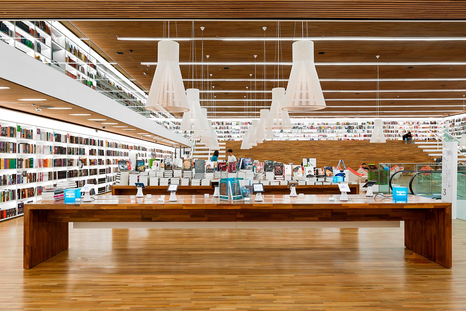 Une grande librairie avec des lampes Magnum suspendues au-dessus des tables.
