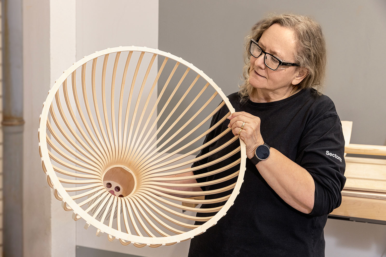 A woman looking closely at a lamp shade.