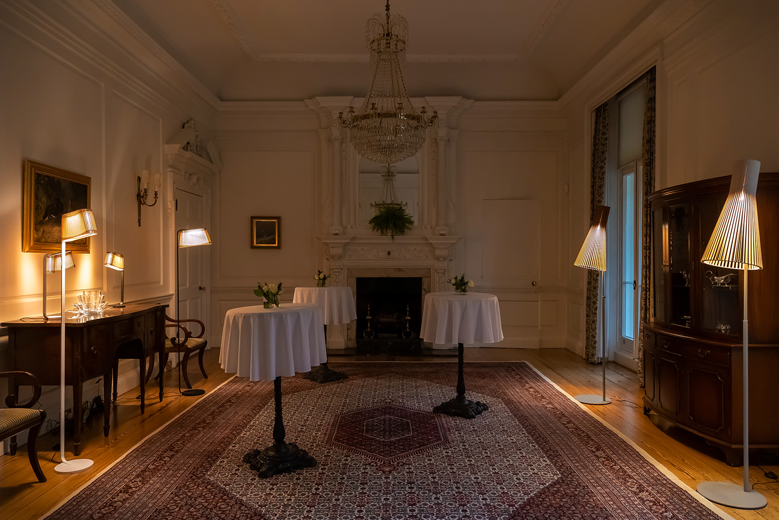 Lit table and floor lamps in a traditionally decorated room.